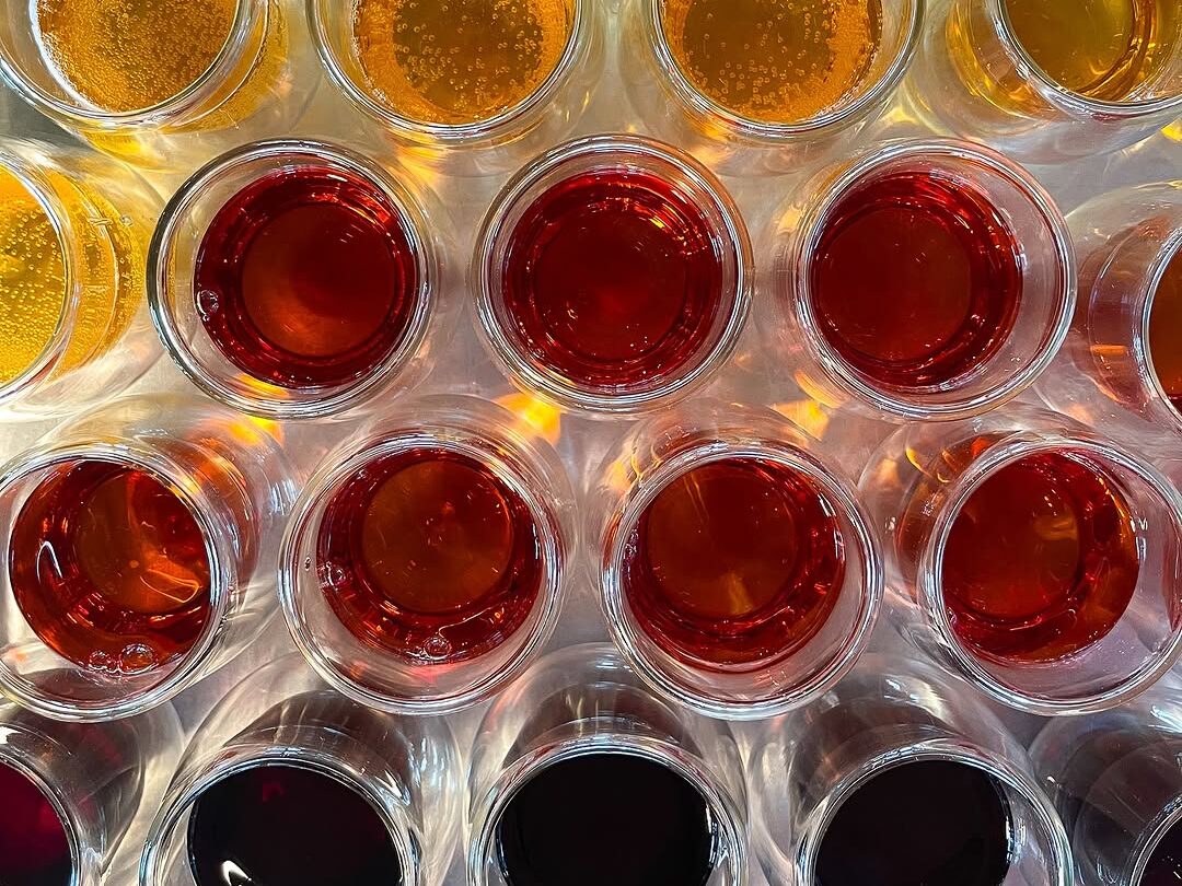 Colorful assortment of liquids in small glass cups for tasting or display.