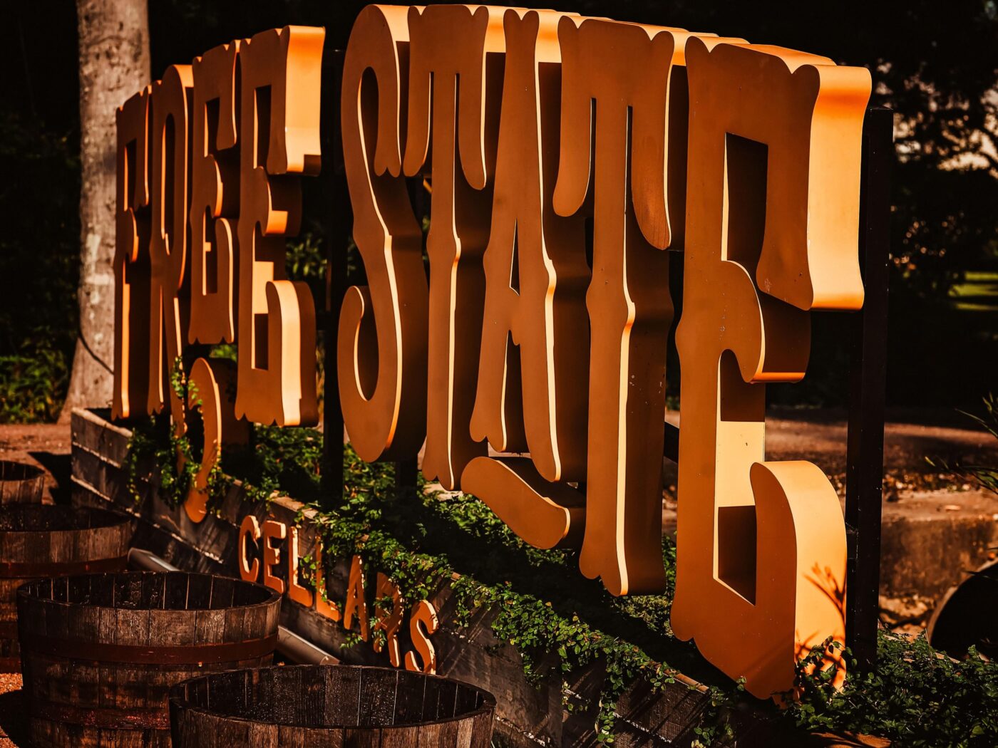 Large North State Cellars sign illuminated at sunset with trees and flowers in the background.